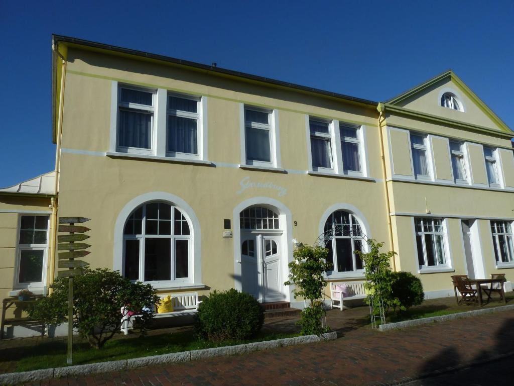 een geel huis met een witte deur en ramen bij Haus Strandburg in Wangerooge