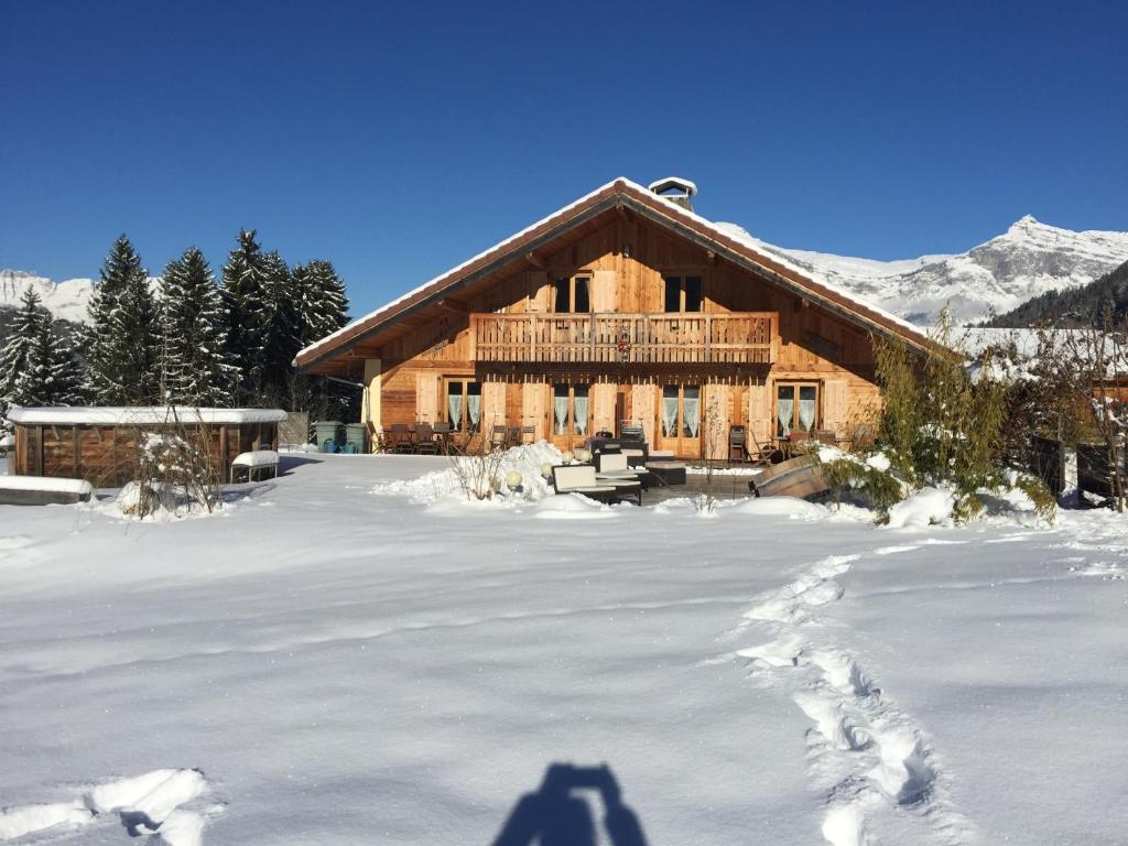 une cabane en rondins dans la neige avec une ombre dans l'établissement Appartement Andromède 25 minutes de Chamonix, à Saint-Gervais-les-Bains