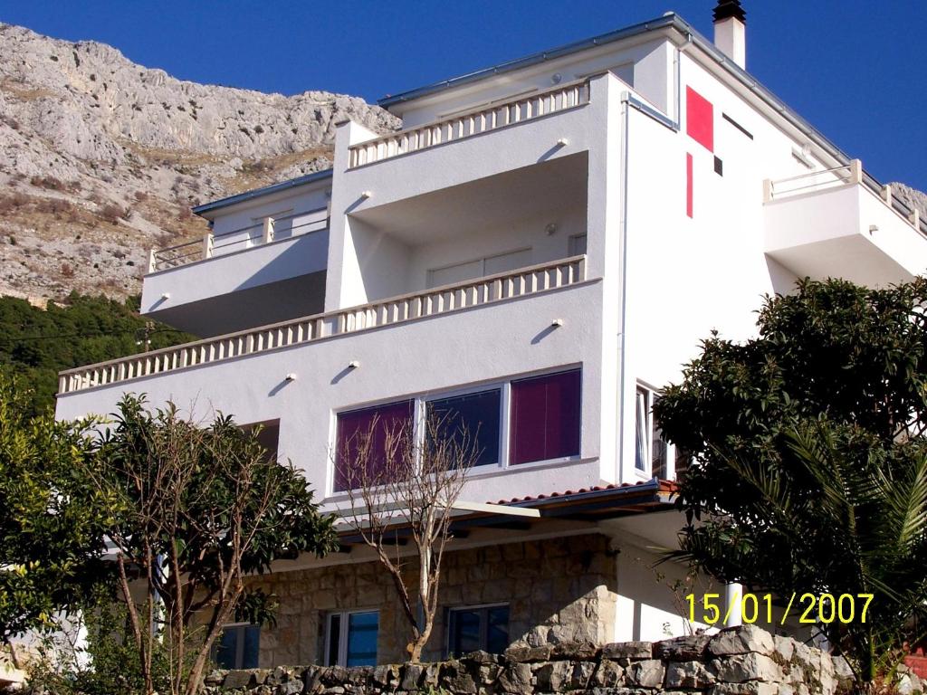 a white building with a mountain in the background at Apartments Perdijic Nemira in Omiš
