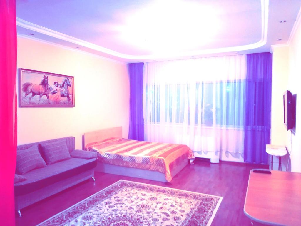 een woonkamer met een bank en een bed bij Chupa Chups apartment on Dostyk 5/1 str in Astana