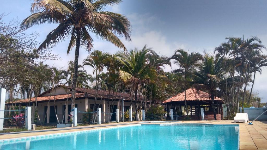 um resort com piscina e palmeiras em Pousada Jorai e Camping em Bertioga