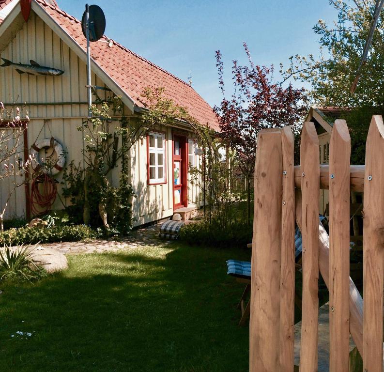 uma cerca de madeira em frente a uma casa em Kleines Haus am Hafen - ruhig und grün am Ortsrand em Prerow