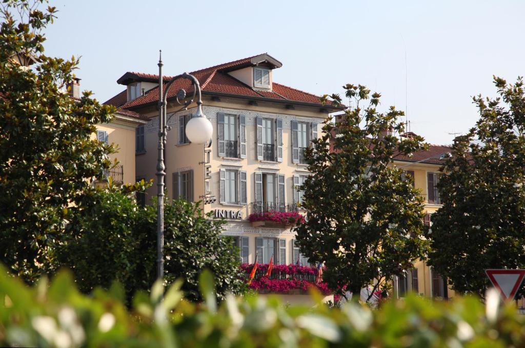 un grand bâtiment avec des arbres devant lui dans l'établissement Intra Hotel, à Verbania