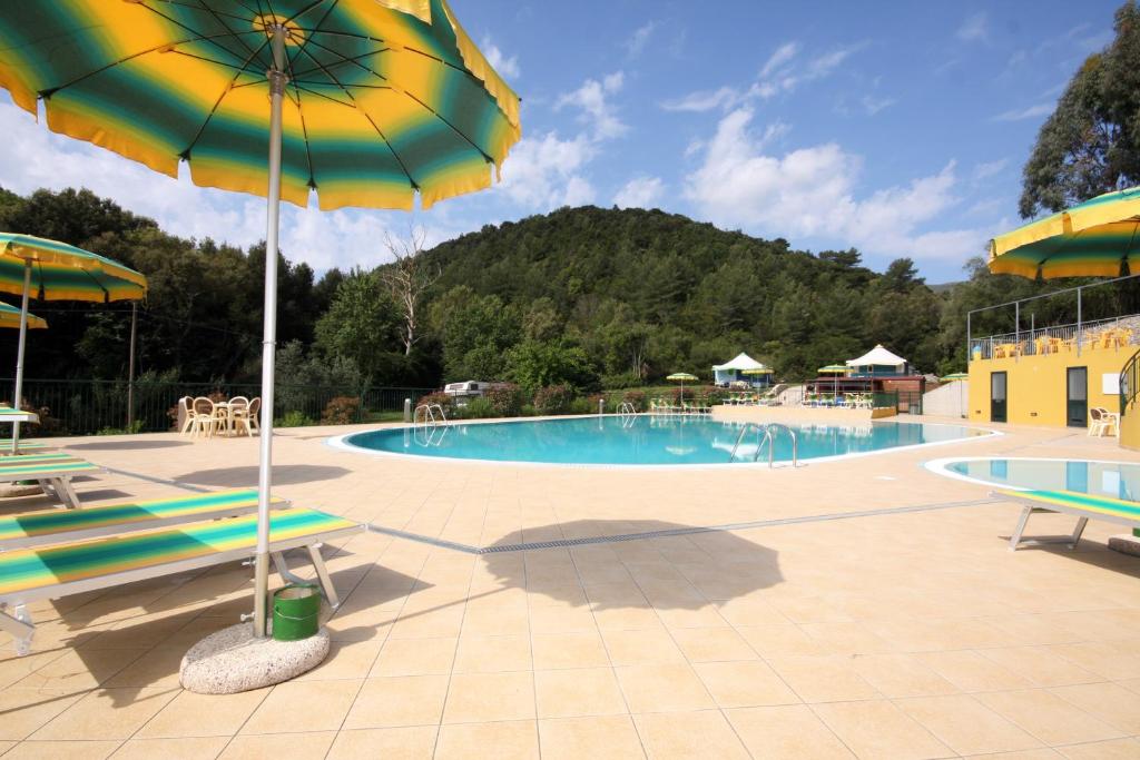 a swimming pool with two chairs and an umbrella at Camping Village Canapai in Rio Marina