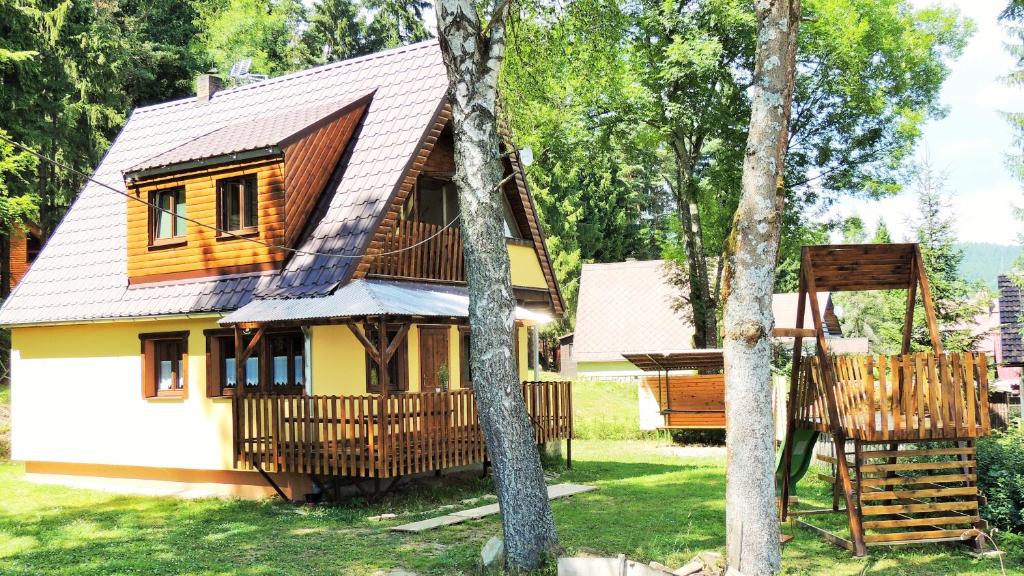 une petite maison jaune et blanche avec des arbres dans l'établissement Chata Sandra, à Lipno nad Vltavou