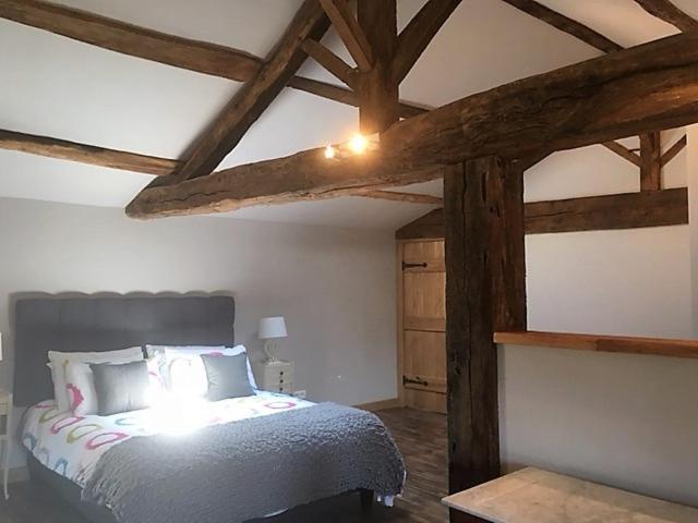 Schlafzimmer mit einem großen Bett mit Holzbalken in der Unterkunft Les Rochers in La Forêt-sur-Sèvre