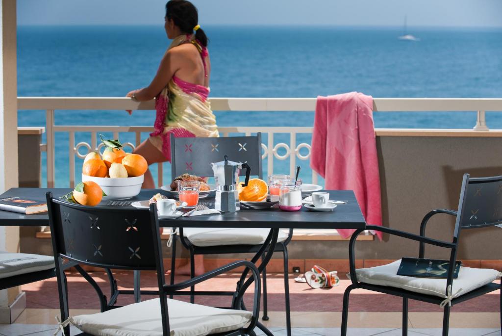 una mujer de pie en un balcón con una mesa con fruta en Casa Vacanze Samira en Fondachello