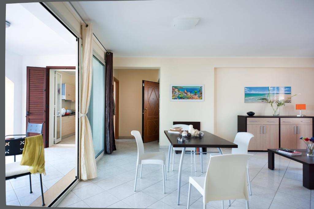 a dining room with white chairs and a table at Casa Vacanze Samira in Fondachello