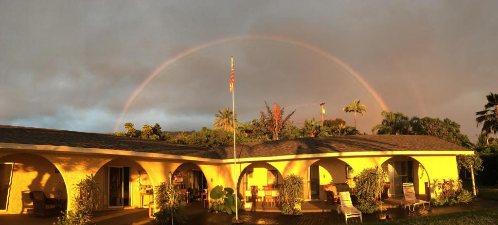a building with a rainbow in the sky behind it at Kona Bayview Inn in Captain Cook