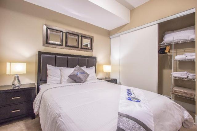 a bedroom with a large white bed and a closet at Platinum Suites Furnished Executive Suites in Mississauga