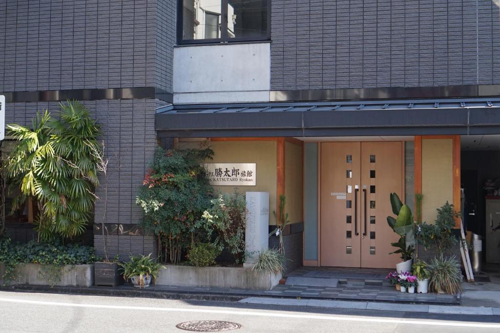 einer Vordertür eines Gebäudes mit Pflanzen in der Unterkunft Annex Katsutaro Ryokan in Tokio