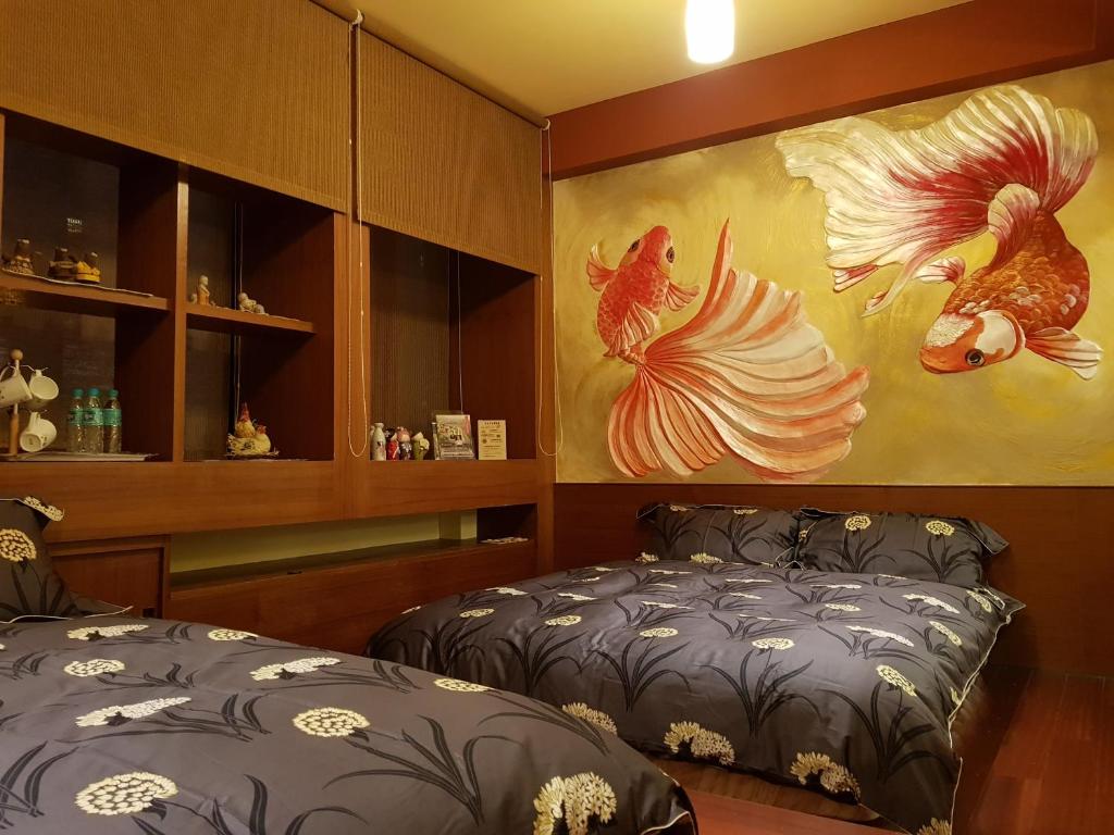 a room with two beds and a painting on the wall at Beautifl Sweet Warm B&amp;B in Hualien City
