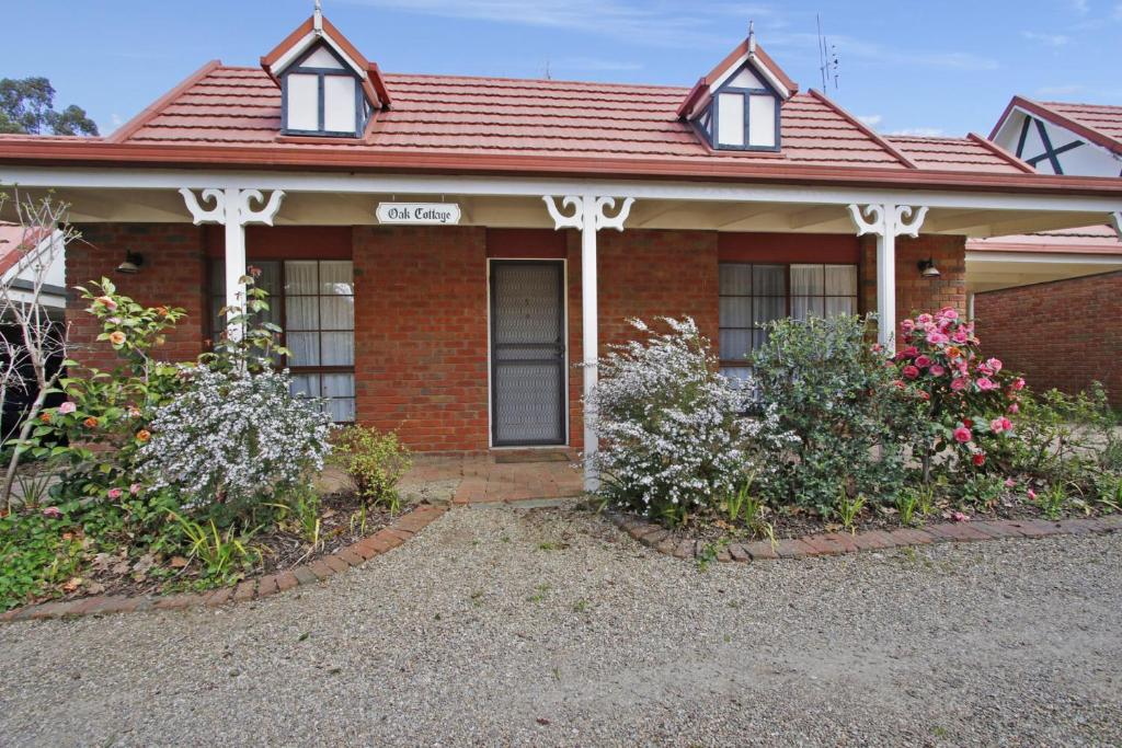 a red brick house with flowers in front of it at Oak Cottage - Tudor Village Unit 5 in Bright