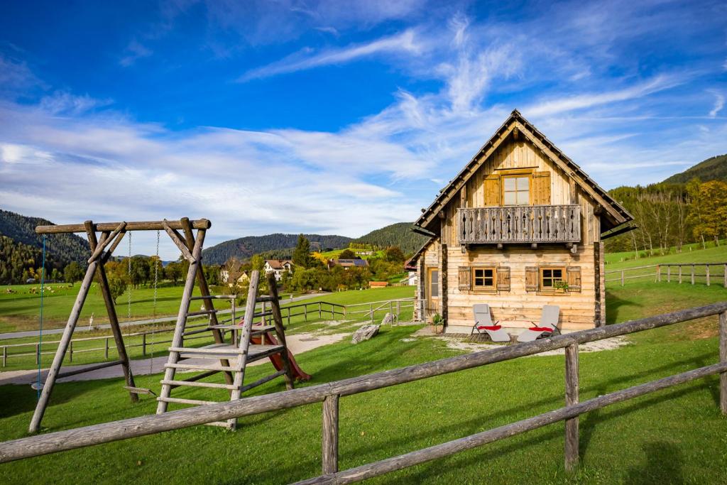 une cabane en rondins avec une balançoire et une maison dans l'établissement Feriendorf Lassing, à Göstling an der Ybbs