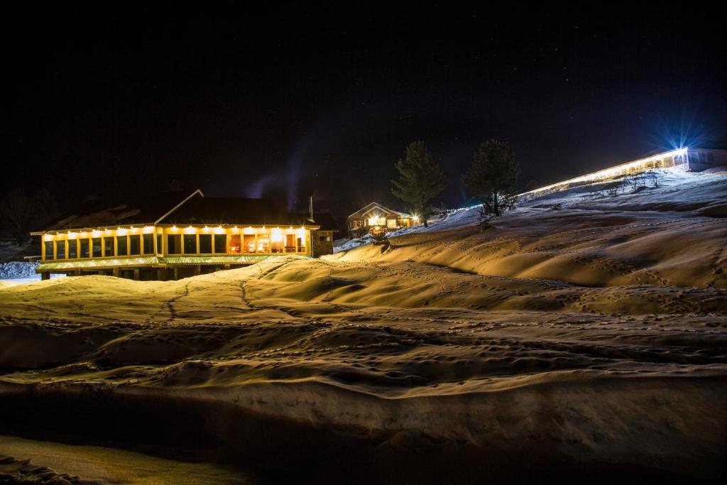 a snowy hill with a building in the background at night at Nedous Hotel Gulmarg in Gulmarg
