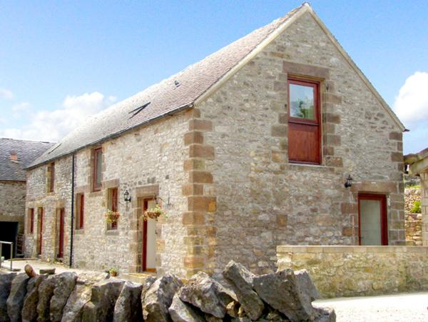 a stone house with a stone wall in front of it at Nuffies Cottage in Elton