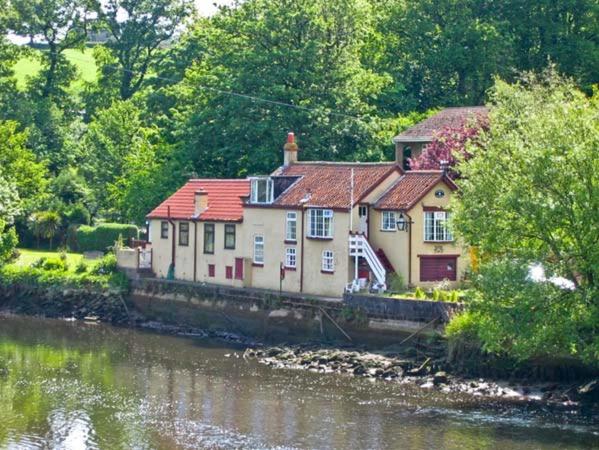 a house sitting on the side of a river at Waterloo Cottage Annexe in Ruswarp