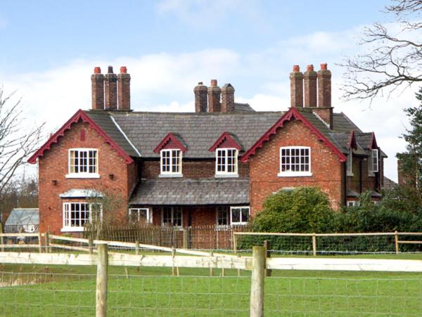 uma grande casa de tijolos vermelhos com uma cerca em frente em Dairy Apartment 2 em Knutsford