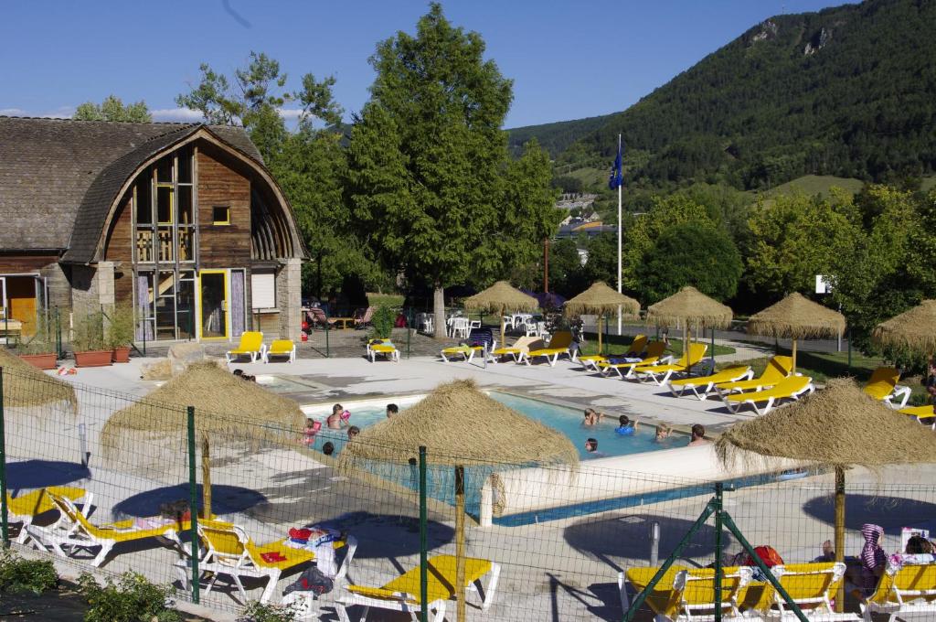 ein Resort mit einem Pool mit Stühlen und Sonnenschirmen in der Unterkunft Village de Gites le Colombier in Mende