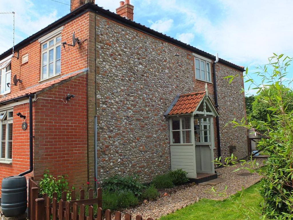 une vieille maison en briques avec une petite porte sur elle dans l'établissement Beaconsfield Cottage, à Briston