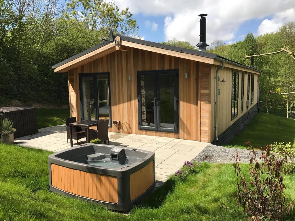 a small cabin with a hot tub in the grass at Shepherd Lodge in Cartmel