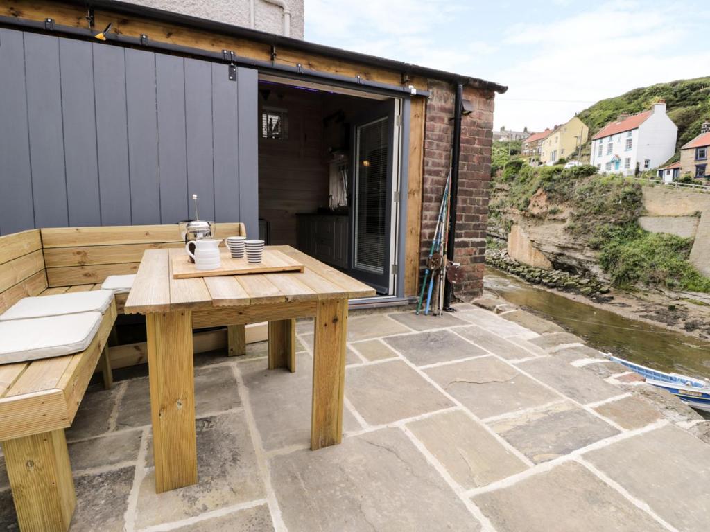 a wooden table and bench on a patio at Old Joiners Shop in Staithes