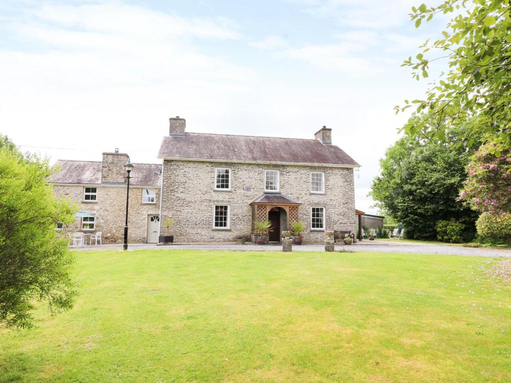 uma antiga casa de pedra com um grande quintal em Dolau Farmhouse em Llanwnen