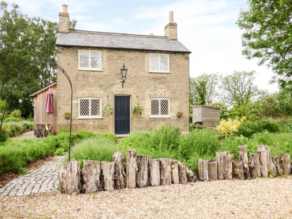 an old brick house with a fence in front of it at Shortmead Cottage in Biggleswade