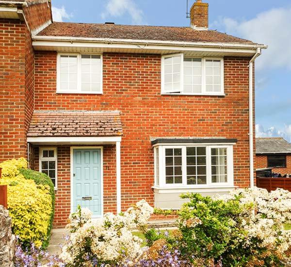 a brick house with a blue door and windows at Leap House in Wareham