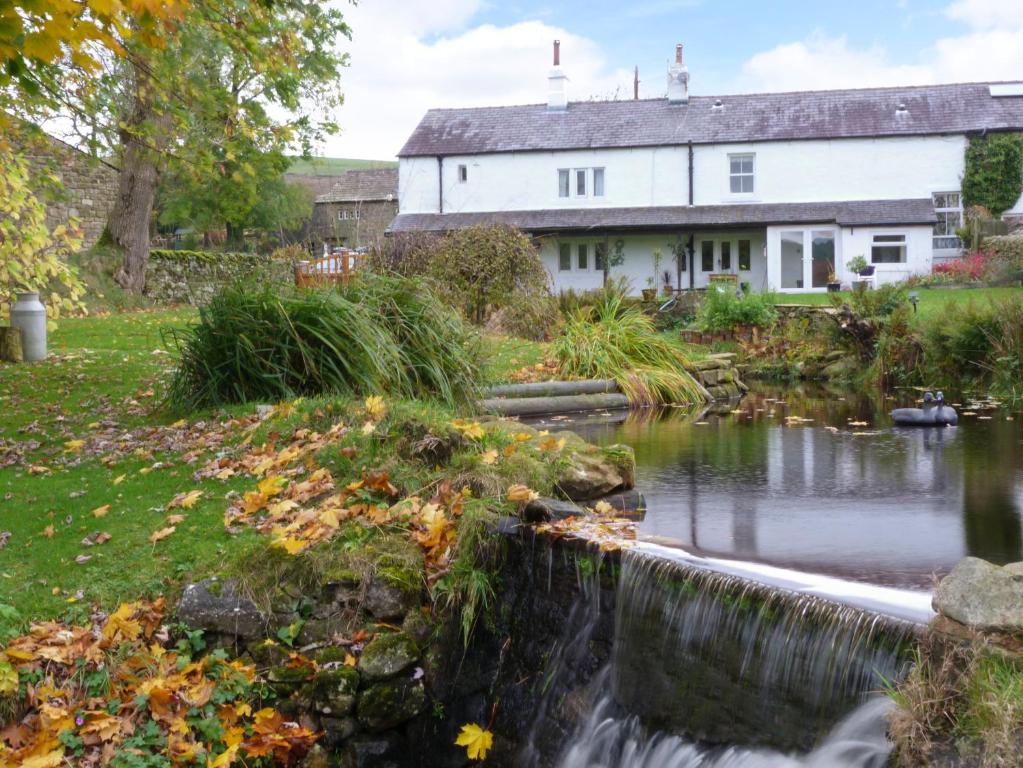 a house and a stream in front of a house at Saetr Cottage in Harrop Fold