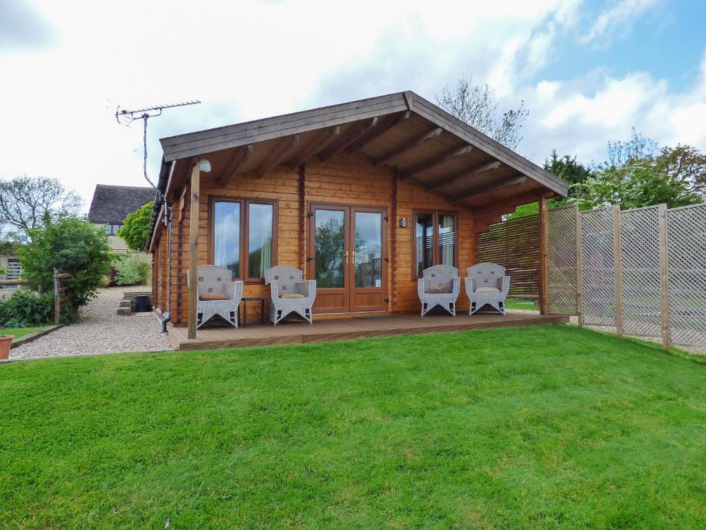 a log cabin with chairs on a lawn at Pennylands Hill View Lodge in Broadway