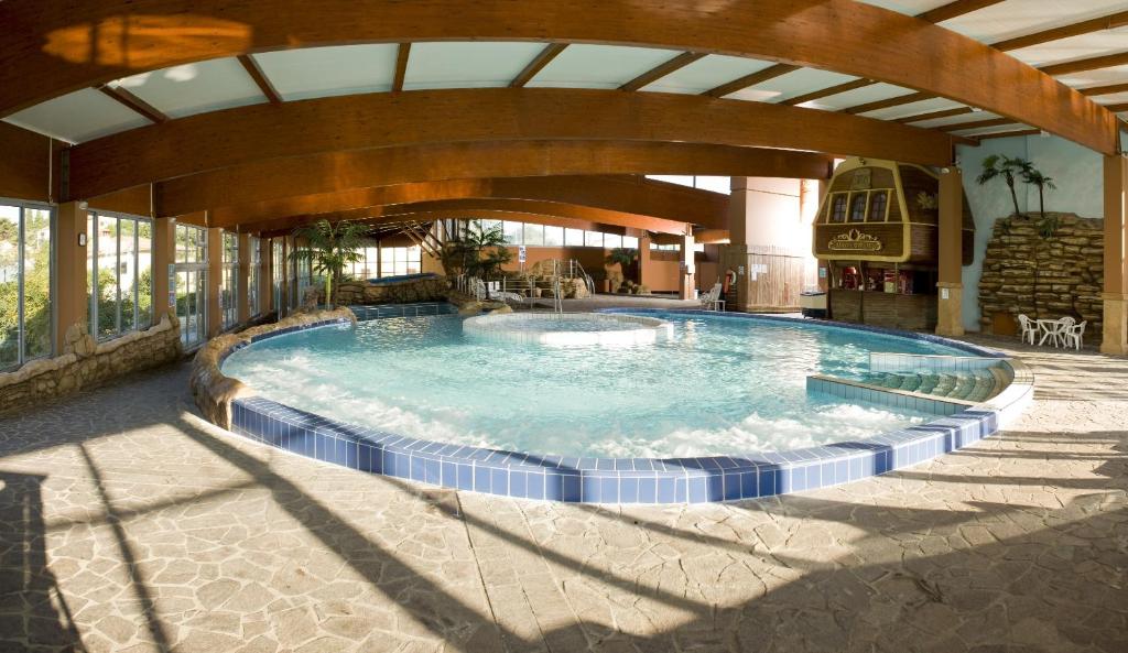 a large swimming pool in a building with an archway at Hotel Aquapark Žusterna in Koper
