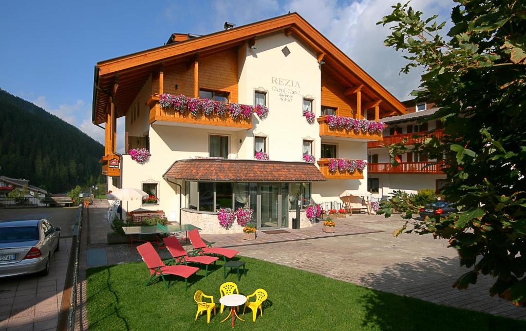 un bâtiment avec des chaises et une table devant lui dans l'établissement Garni Hotel Rezia, à Selva di Val Gardena