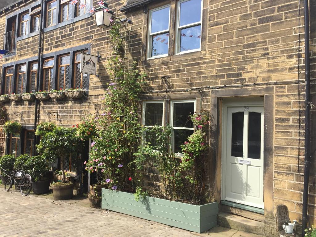 a brick building with a white door and flowers at 29 Main Street in Haworth