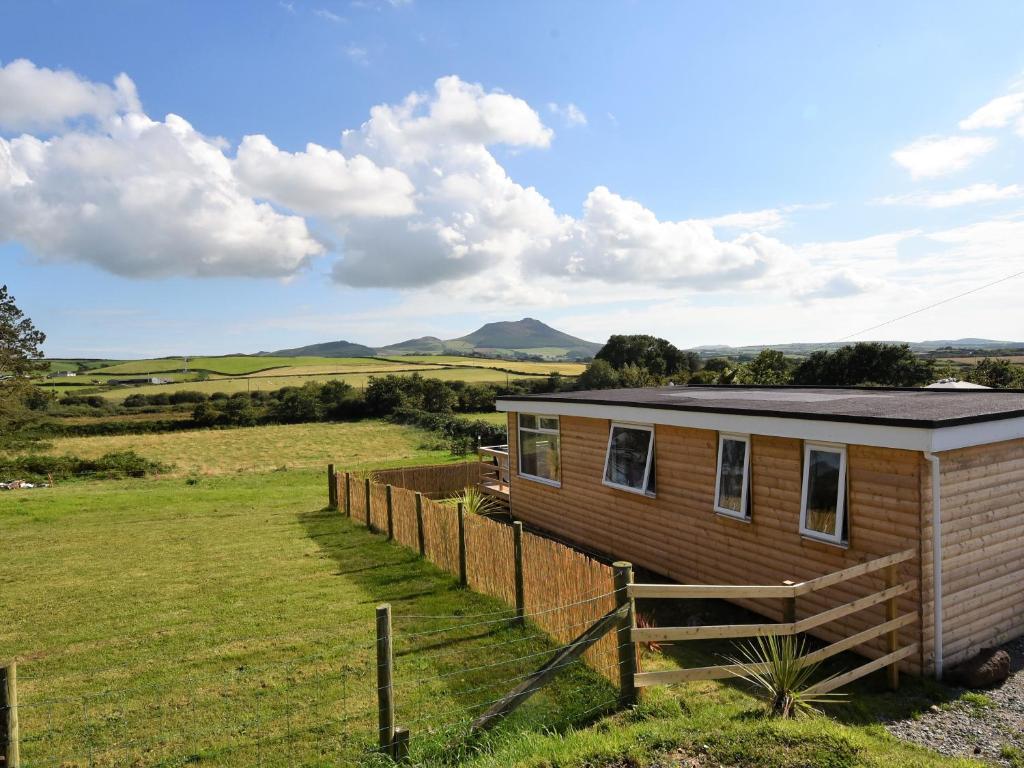 a tiny house in a field with a fence at Y Caban Clyd in Morfa Nefyn