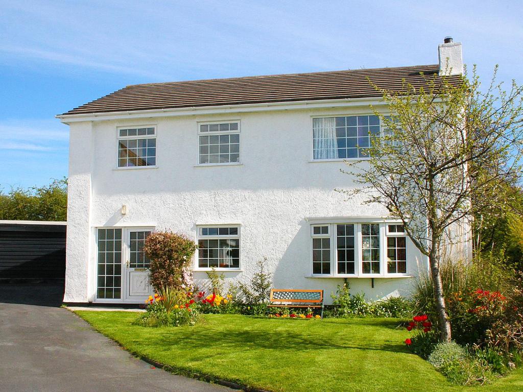 una casa blanca con un banco en el patio en Anglesey White Haven en Llandegfan