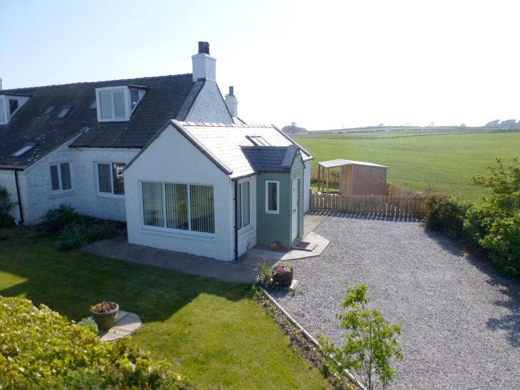 a white house with a green door and a yard at Simmer Dim in Kirkbean