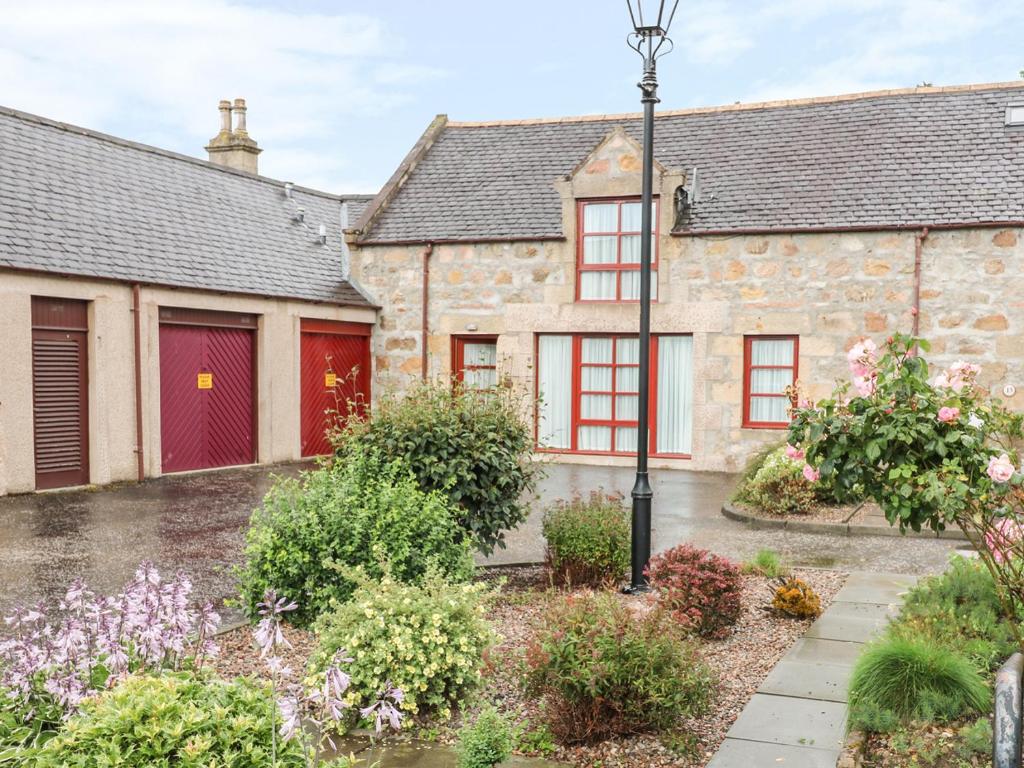 an old stone house with red doors and a courtyard at The Farm Steading in Aberlour