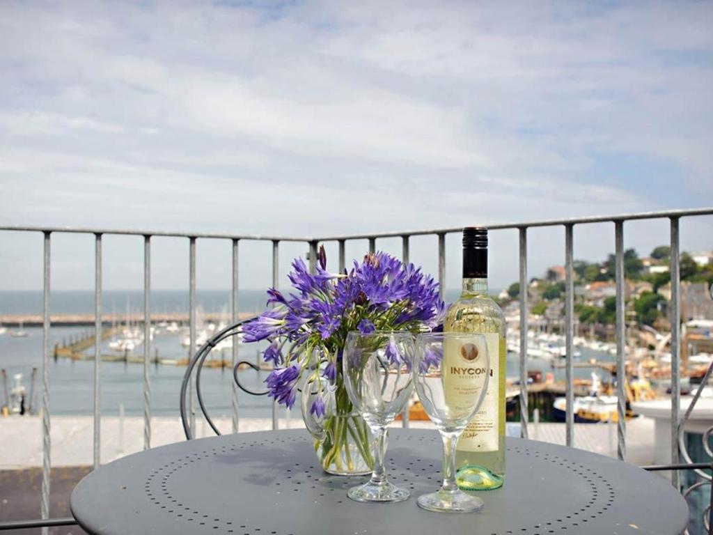een fles wijn en een glas en bloemen op een tafel bij Blue Horizon in Brixham