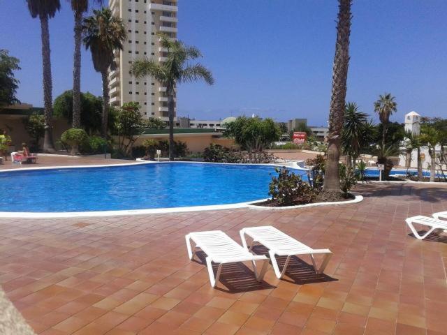 dos bancos blancos sentados junto a una piscina con palmeras en Golden Dreams & Perfect for you *****, en Adeje