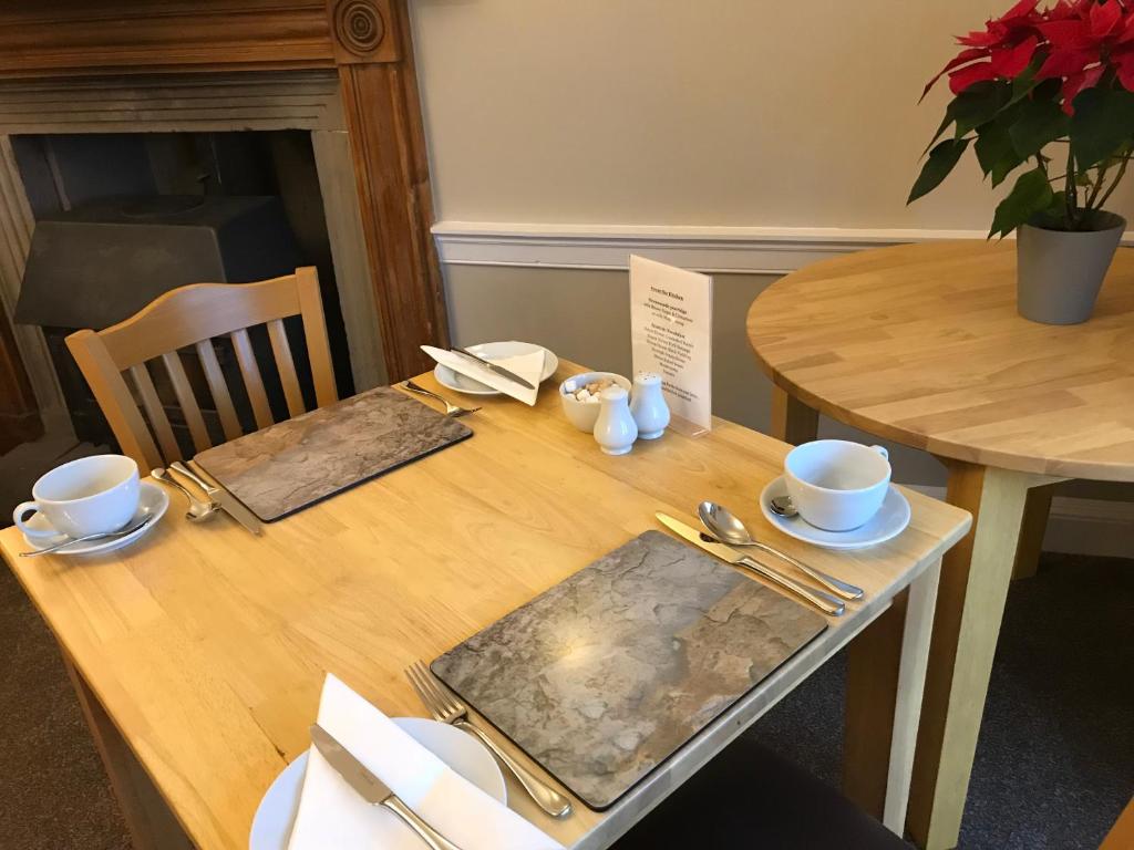 una mesa de madera con tazas y platillos. en West Plean House en Stirling