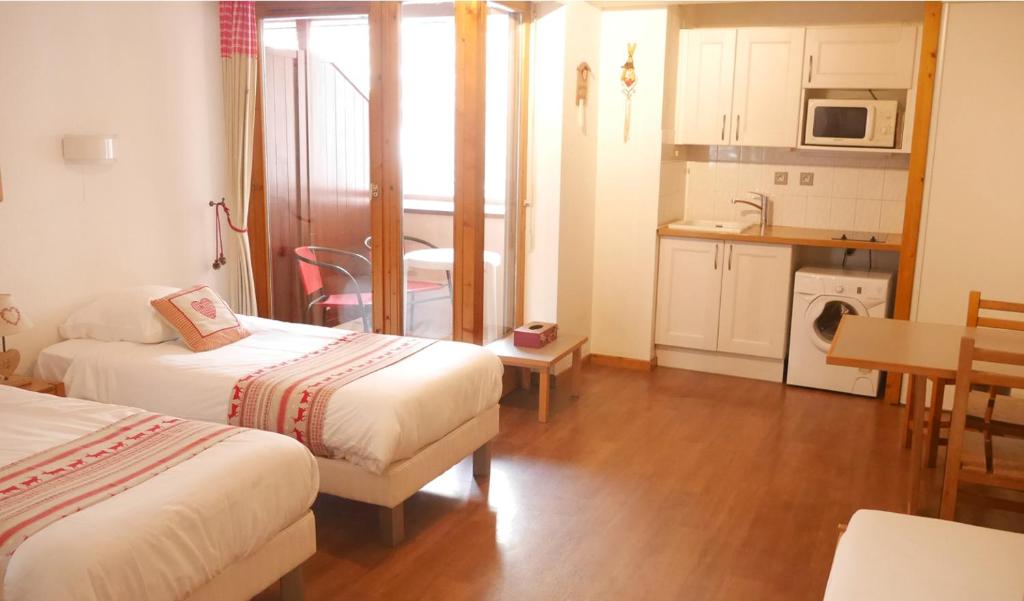a room with two beds and a kitchen with a table at Le Grand Chalet - Le Studio in Brides-les-Bains