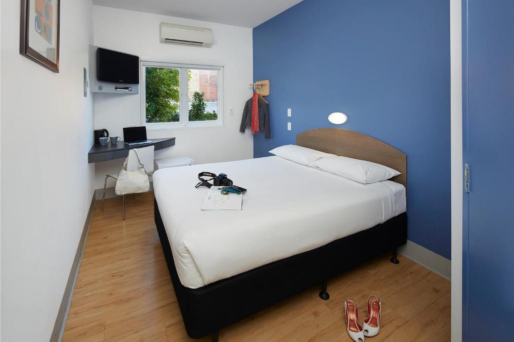 a bedroom with a white bed and white walls at ibis Budget Perth Airport in Perth