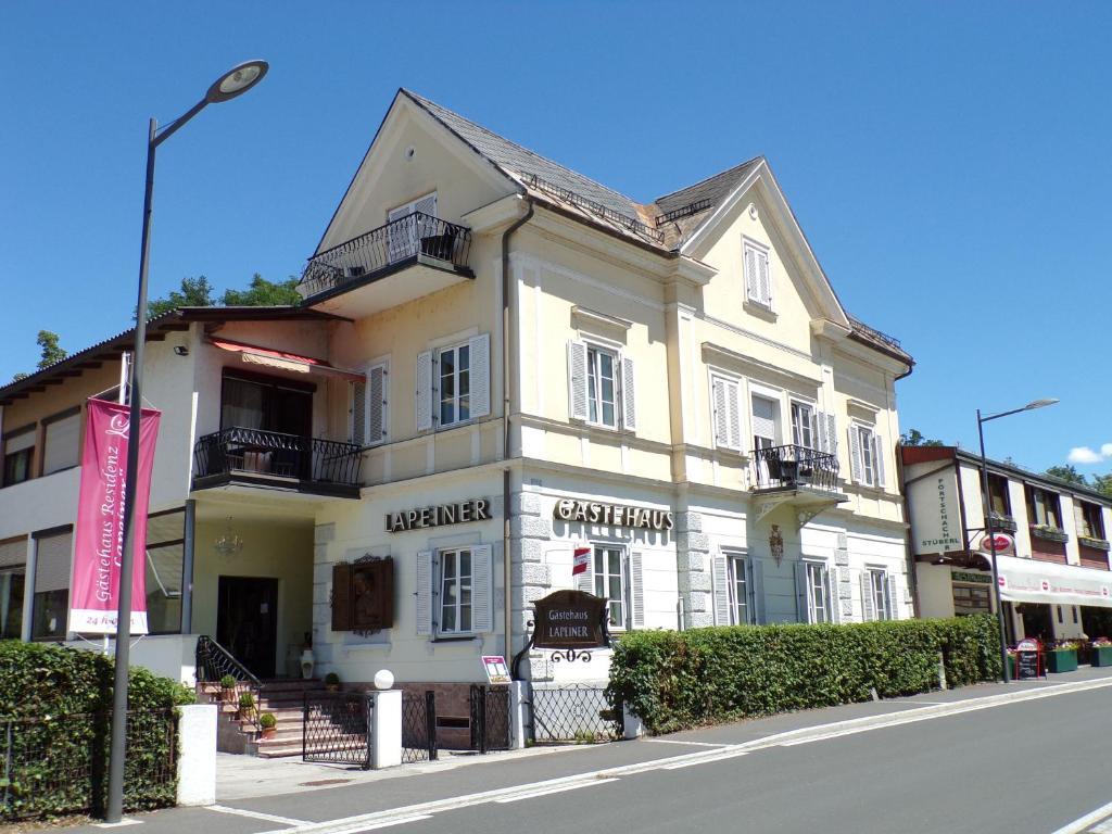 ein weißes Gebäude an der Straßenseite in der Unterkunft Gästehaus Residenz Lapeiner in Pörtschach am Wörthersee