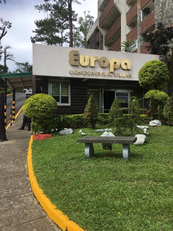 a bench in the grass in front of a building at M&M Residence in Baguio