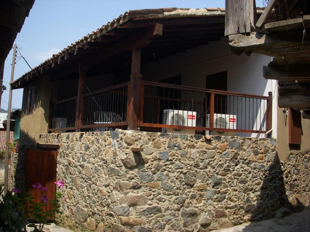 a stone wall in front of a house with a balcony at Patriko Traditional House in Kakopetria