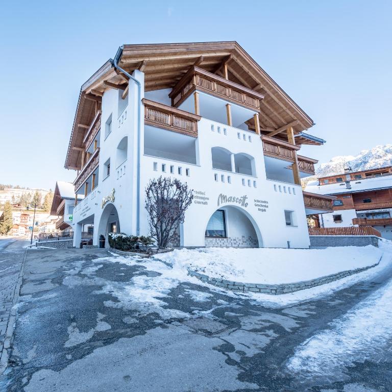 a large white building with snow on the ground at Ciasa Mascotte in San Vigilio Di Marebbe