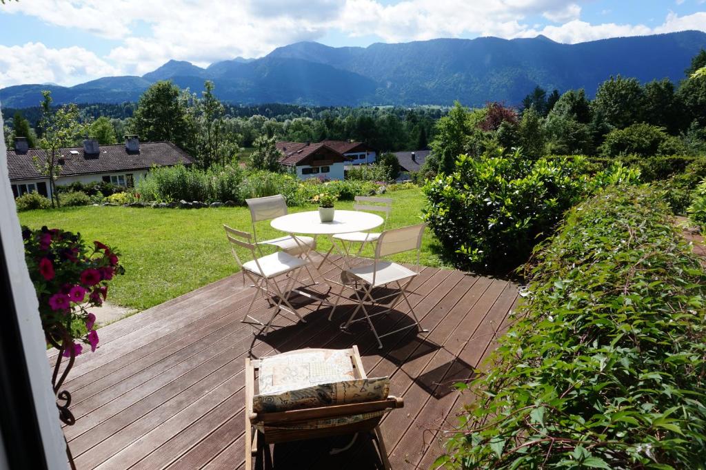 a wooden deck with a table and chairs and mountains at Studio Murnauer Moos in Murnau am Staffelsee