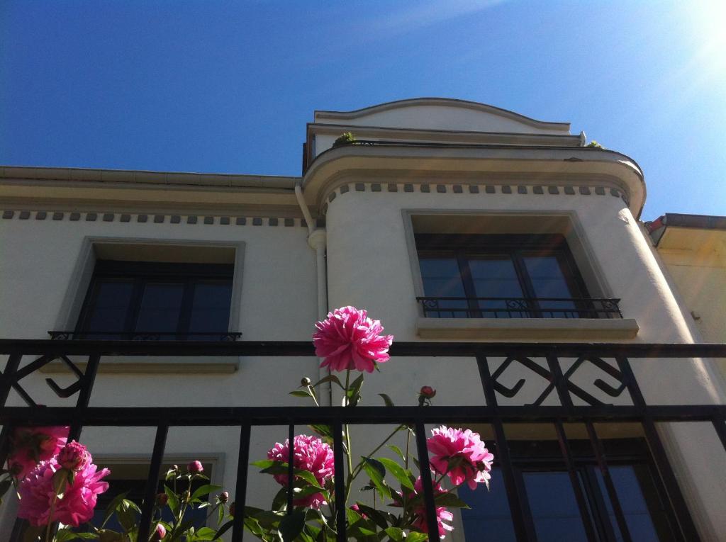 Um edifício com flores cor-de-rosa à frente. em Les Jardins de l'Ile em Longeville-lès-Metz