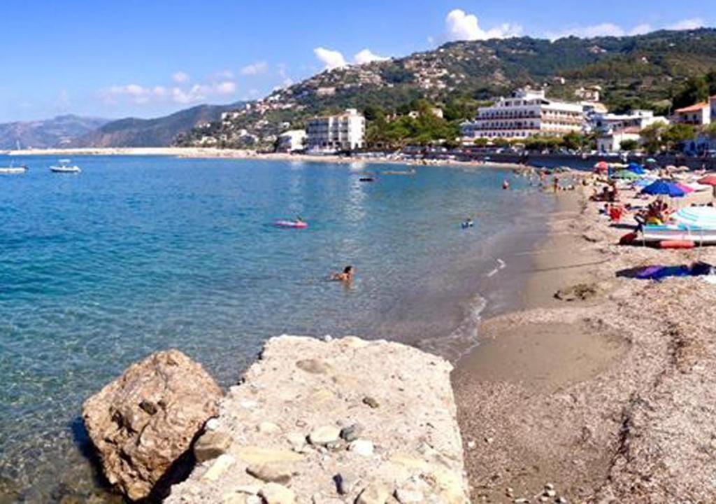 a beach with a bunch of people swimming in the water at Cordovena in Capo dʼOrlando